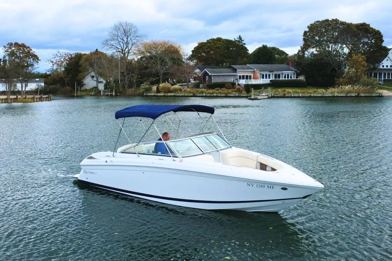The Image of 2010 Cobalt 242 boat cruising on a serene lake with houses in the background. - 0