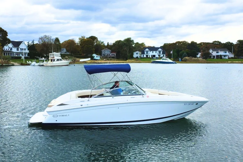 Slide: The Image of 2010 Cobalt 242 boat cruising on a serene lake with houses in the background. - 1