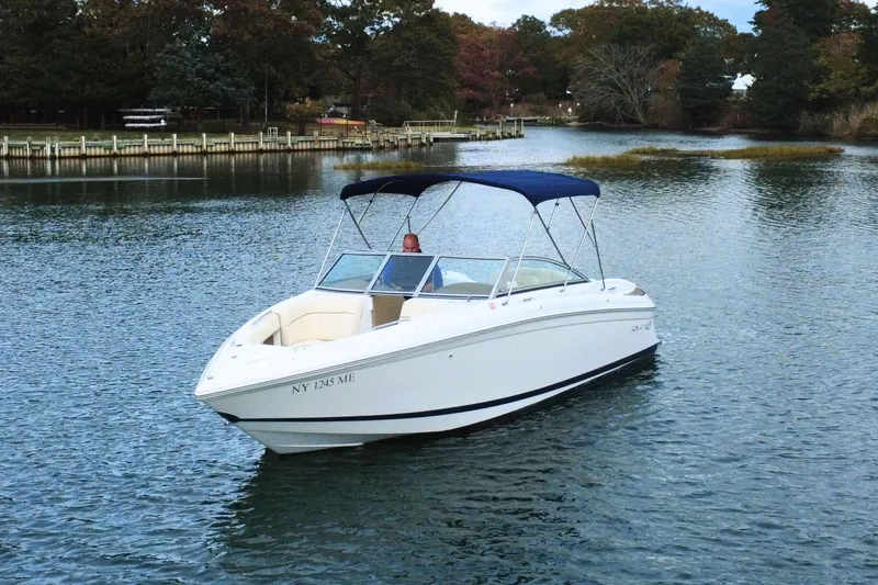 Slide: The Image of 2010 Cobalt 242 boat with canopy on calm water, surrounded by trees. - 2