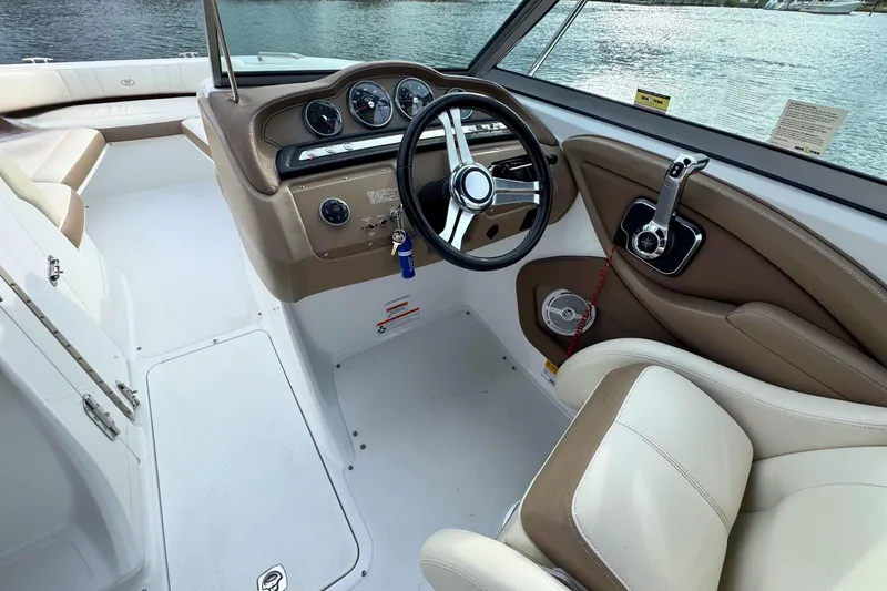 Slide: The Image of 2010 Cobalt 242 boat interior with steering wheel and control panel, overlooking water. - 20