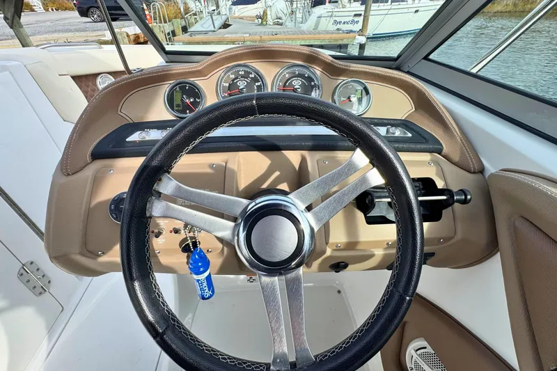 Slide: The Image of Steering wheel and dashboard of a 2010 Cobalt 242 boat, featuring gauges and controls. - 21