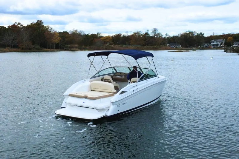 Slide: The Image of 2010 Cobalt 242 boat cruising on a serene lake with scenic background. - 3