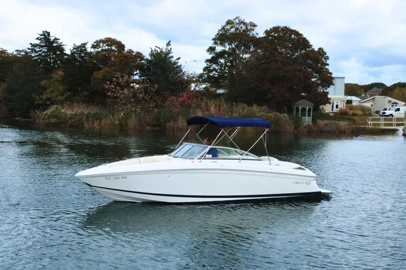 Slide: The Image of 2010 Cobalt 242 boat cruising on a calm lake with scenic background. - 4