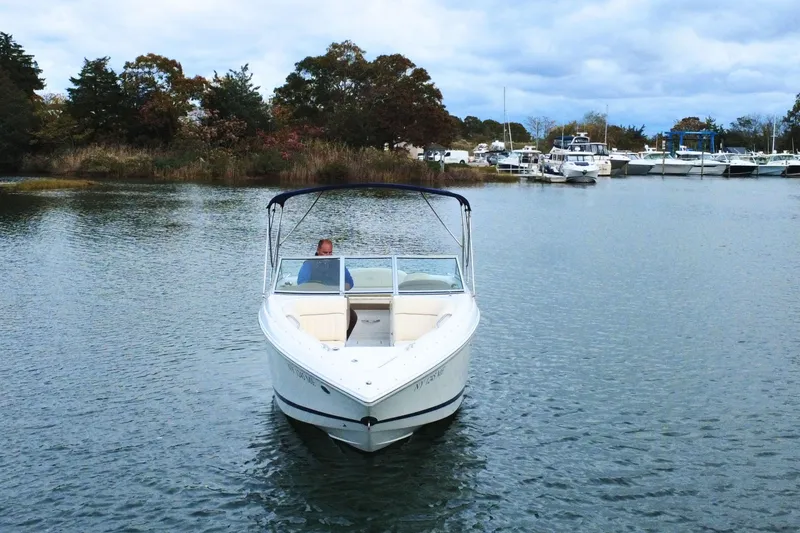 Slide: The Image of 2010 Cobalt 242 boat cruising on a calm lake with trees and marina in background. - 6