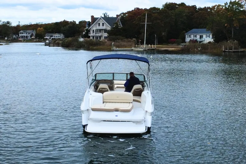 Slide: The Image of 2010 Cobalt 242 boat cruising on a scenic lake with houses in the background. - 7