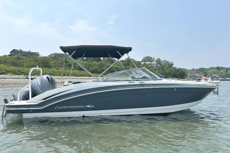 Slide: The Image of 2021 Chaparral 230 Suncoast boat with canopy on calm water near shoreline. - 0