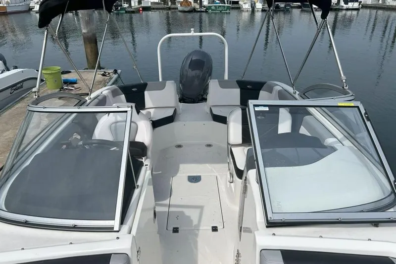 Slide: The Image of 2021 Chaparral 230 Suncoast boat docked at marina, featuring open deck and seating. - 4