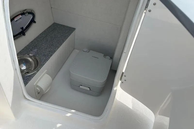Slide: The Image of 2021 Chaparral 230 Suncoast boat interior with sink and portable toilet. - 9
