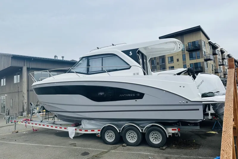 Slide: The Image of 2026 Beneteau Antares 9 V2 boat on trailer, parked near modern buildings. - 1