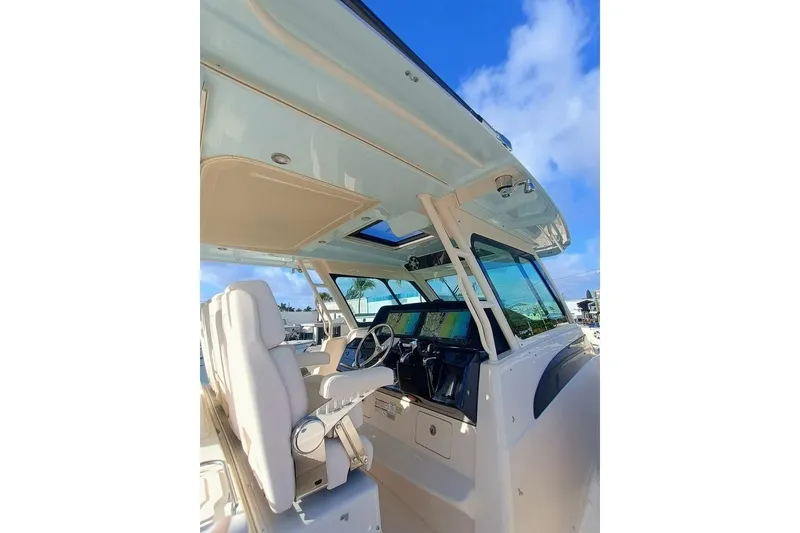 Slide: The Image of 2025 Grady-White Canyon 456 boat interior with helm, under clear blue sky. - 6