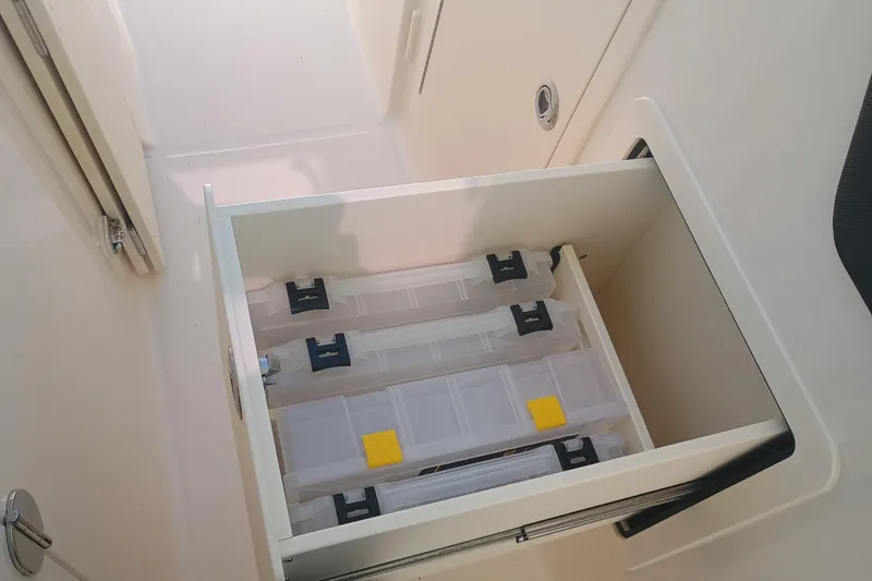 Slide: The Image of Storage compartment with organized containers in a 2025 Grady-White Canyon 456 boat. - 11