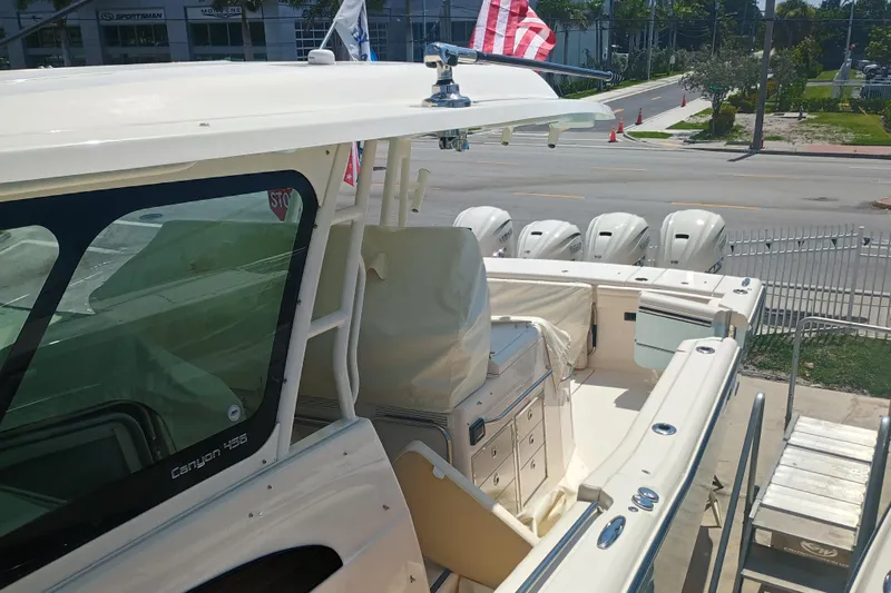 Slide: The Image of 2025 Grady-White Canyon 456 boat with multiple outboard engines, docked near a road. - 19