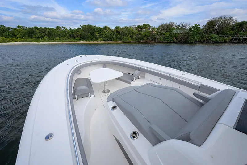 Slide: The Image of 2024 Valhalla Boatworks V-46, luxurious deck with seating and table, near scenic shoreline. - 22