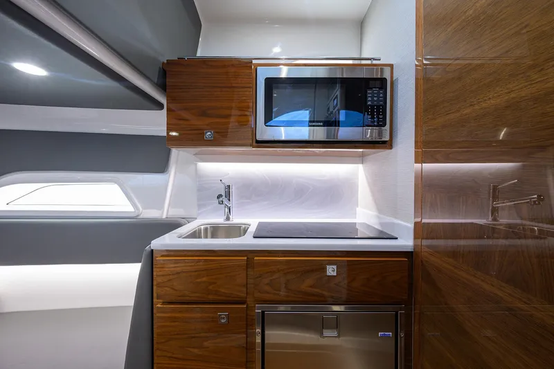 Slide: The Image of 2024 Valhalla V-46 boat interior kitchen with microwave, sink, and wooden cabinetry. - 51