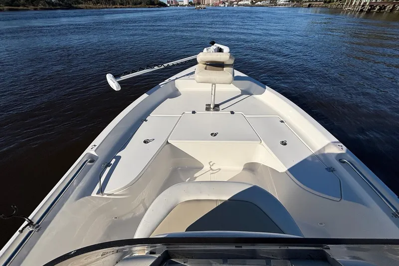 Slide: The Image of 2022 Bulls Bay 2000 boat on calm water, featuring a spacious deck and seating area. - 14