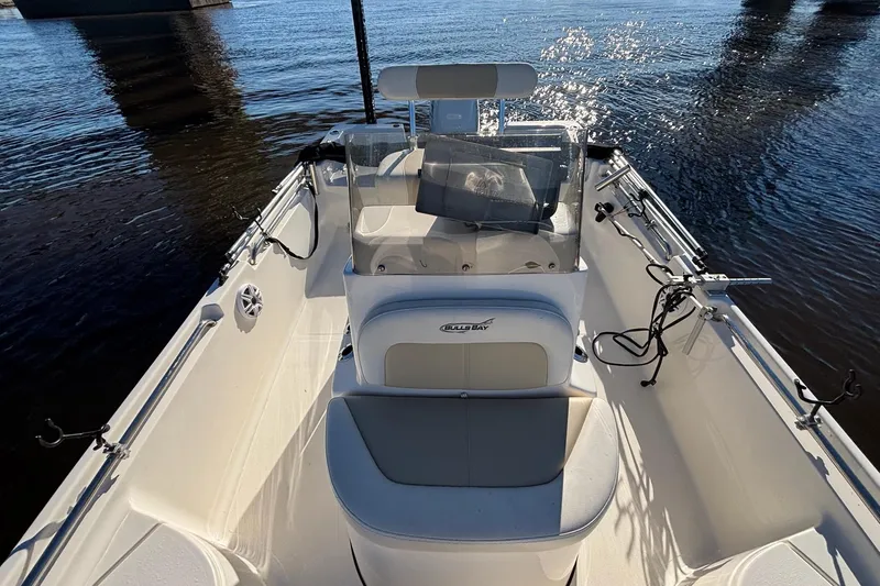 Slide: The Image of 2022 Bulls Bay 2000 boat interior with seating and steering console on calm water. - 15
