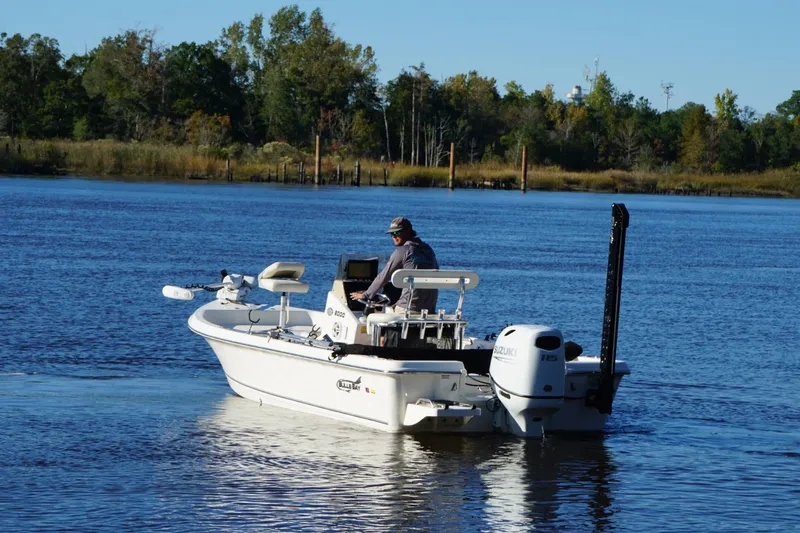 Slide: The Image of Bulls Bay 2000 boat on a serene lake, 2022 model, with lush greenery in the background. - 5