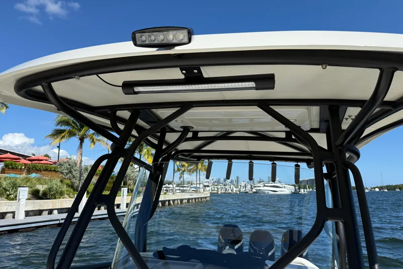 Slide: The Image of 2003 Hydra-Sports Vector 3300 CC boat with T-top, docked by palm trees and water. - 9