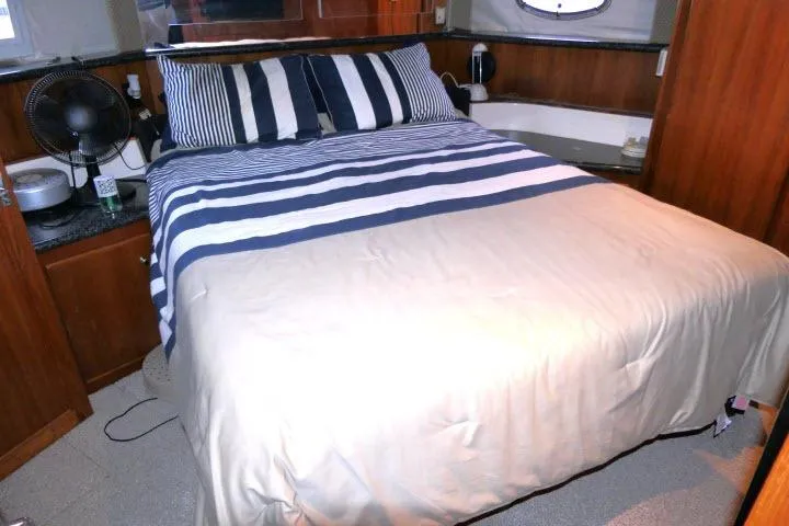 Slide: The Image of Cozy bedroom in 2000 Carver 406 Motor Yacht with striped bedding and wooden accents. - 10