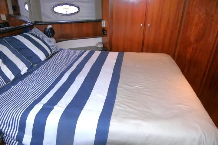Slide: The Image of Interior of 2000 Carver 406 Motor Yacht with striped bedding and wooden cabinetry. - 11