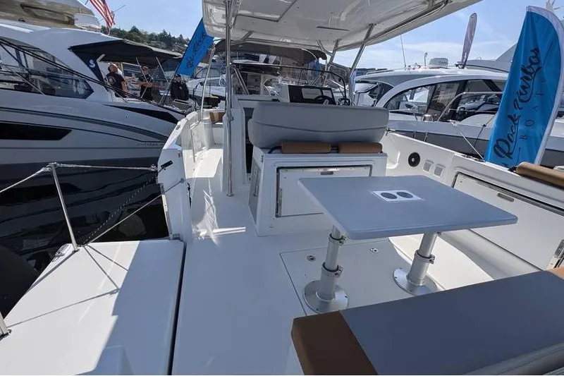 Slide: The Image of 2024 Beneteau Flyer 9 SPACEdeck boat interior with seating and table, docked at marina. - 10