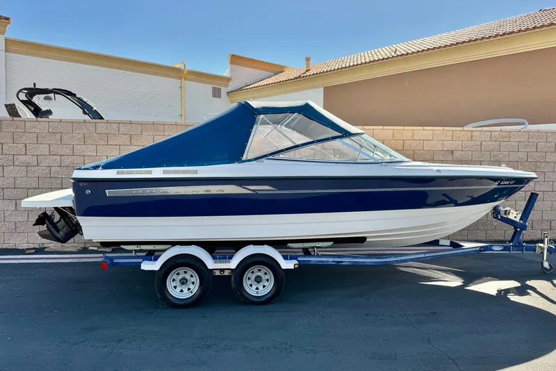 The Image of 2006 Bayliner 215 Bowrider boat on trailer, blue and white exterior, parked outdoors. - 0
