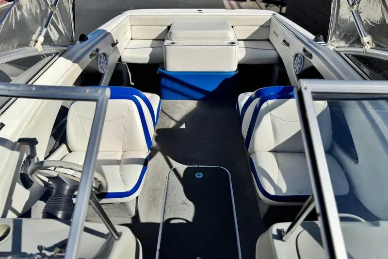 Slide: The Image of 2006 Bayliner 215 Bowrider interior with white and blue seating, steering wheel, and carpeted floor. - 12