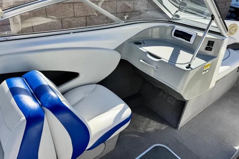 Slide: The Image of 2006 Bayliner 215 Bowrider interior with blue and white seating, dashboard, and cup holder. - 18
