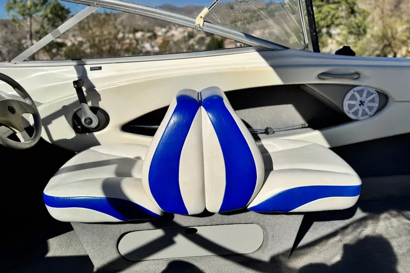 Slide: The Image of 2006 Bayliner 215 Bowrider interior with blue and white seating, steering wheel, and speaker. - 20