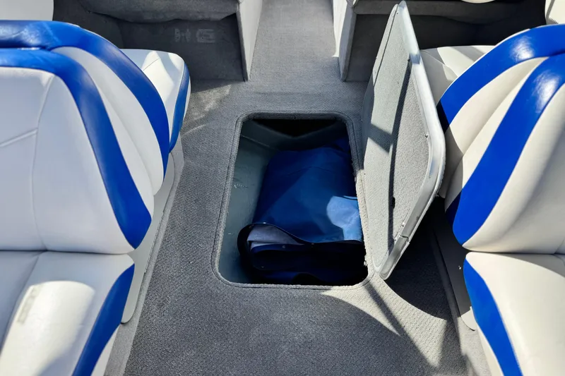 Slide: The Image of 2006 Bayliner 215 Bowrider interior with open storage compartment and blue-white seating. - 21