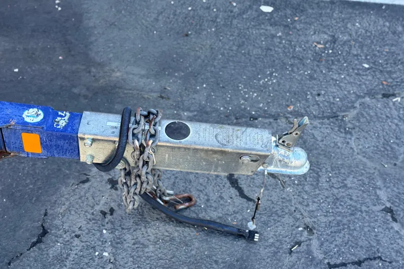 Slide: The Image of Trailer hitch with chains for 2006 Bayliner 215 Bowrider on asphalt surface. - 25