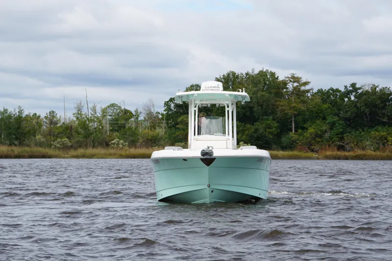 Slide: The Image of 2022 Robalo R242 Center Console boat on a lake with lush green shoreline. - 2