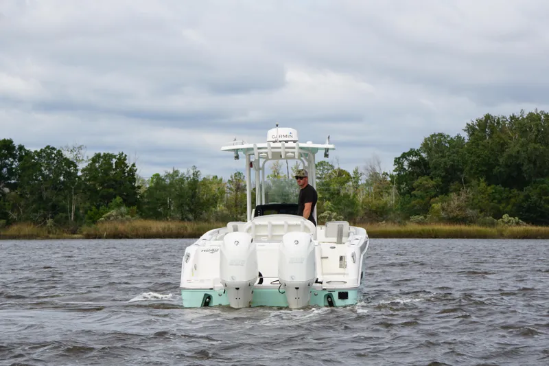 Slide: The Image of 2022 Robalo R242 Center Console boat cruising on a river with lush green trees. - 4