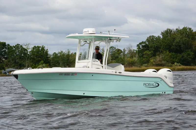 Slide: The Image of 2022 Robalo R242 Center Console boat on water, with trees in the background. - 5