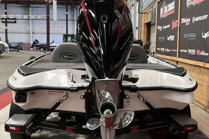 Slide: The Image of 2026 Triton 18 TrX boat in showroom, rear view with powerful outboard motor. - 4