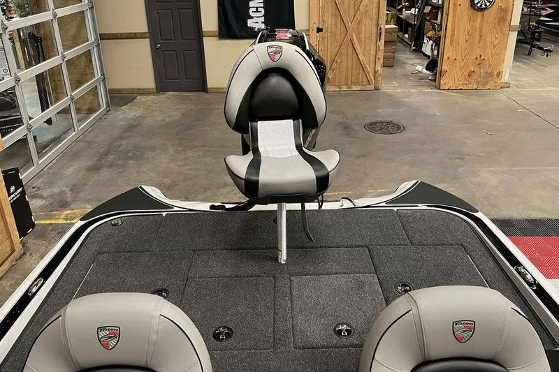 Slide: The Image of 2026 Triton 18 TrX boat interior with gray and black seating in a garage setting. - 8