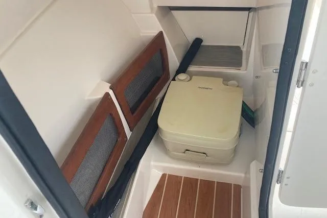 Slide: The Image of 2020 Grady-White Freedom 235 boat interior with portable toilet and wooden flooring. - 11