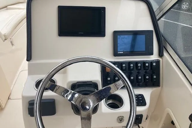 Slide: The Image of 2020 Grady-White Freedom 235 boat dashboard with steering wheel and electronic controls. - 13