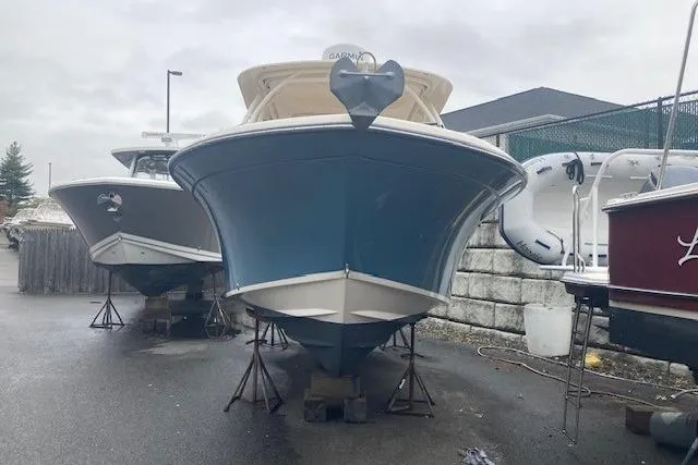 Slide: The Image of 2020 Grady-White Freedom 235 boat on stands, front view, in a marina setting. - 2
