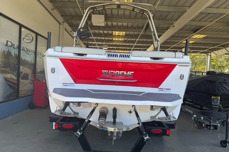 Slide: The Image of 2023 Supreme ZS212 boat rear view in a parking lot with trees and a truck. - 6