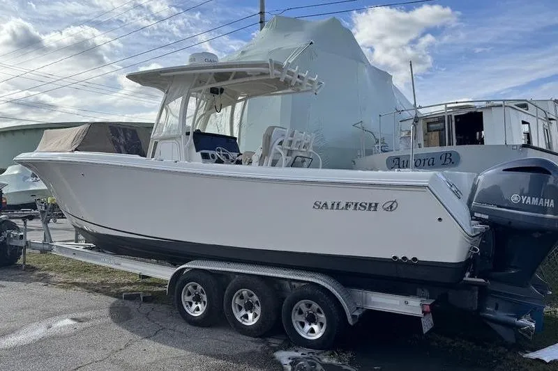 Slide: The Image of 2021 Sailfish 290 CC boat on trailer, featuring Yamaha engines, parked outdoors. - 23