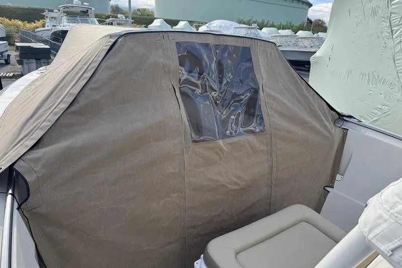 Slide: The Image of 2021 Sailfish 290 CC boat with protective cover and window, showcasing seating area. - 6