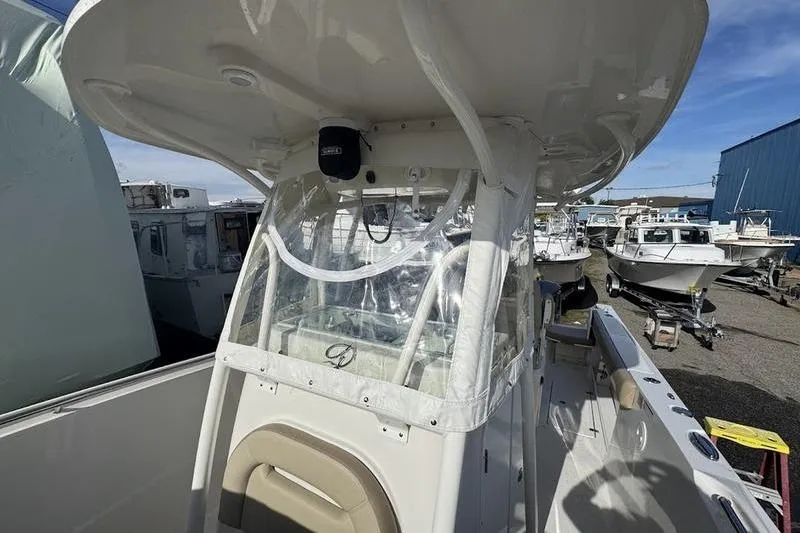 Slide: The Image of 2021 Sailfish 290 CC boat with covered helm, docked among other vessels. - 9