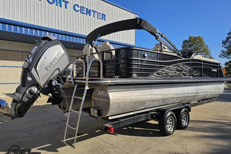 Slide: The Image of 2015 Bennington 2550 QBR pontoon boat on trailer, parked outside a sport center. - 11