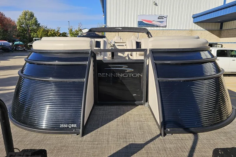 Slide: The Image of 2015 Bennington 2550 QBR pontoon boat at a marina, showcasing sleek design and spacious seating. - 19