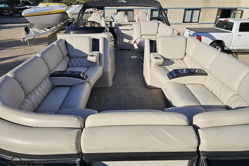 Slide: The Image of 2015 Bennington 2550 QBR pontoon boat with luxurious seating and cup holders, docked outdoors. - 20
