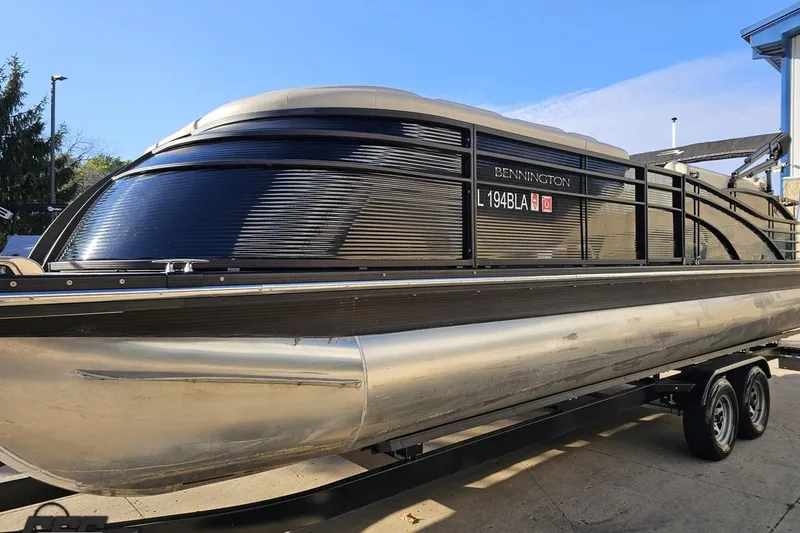 Slide: The Image of 2015 Bennington 2550 QBR pontoon boat on trailer, sleek black design, outdoor setting. - 22