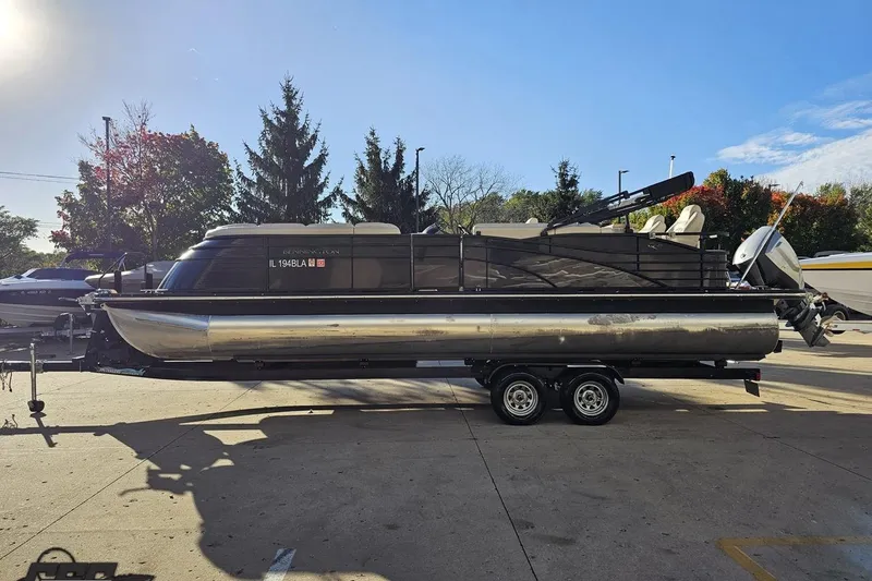 Slide: The Image of 2015 Bennington 2550 QBR pontoon boat on trailer, parked outdoors under clear sky. - 26