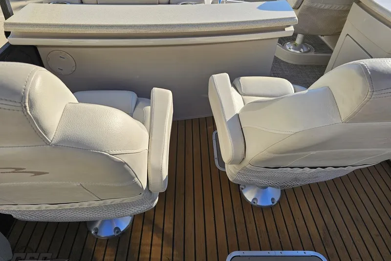 Slide: The Image of Two white seats on a 2015 Bennington 2550 QBR boat with wooden flooring. - 39