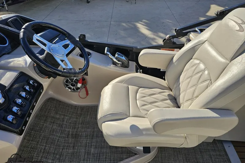 Slide: The Image of 2015 Bennington 2550 QBR boat interior with steering wheel and plush captain's chair. - 56